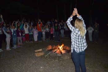 Campers and counselors singing by the fire.