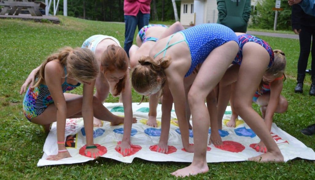 Campers at WeHaKee Camp for Girls playing twister outside using colored shaving cream.