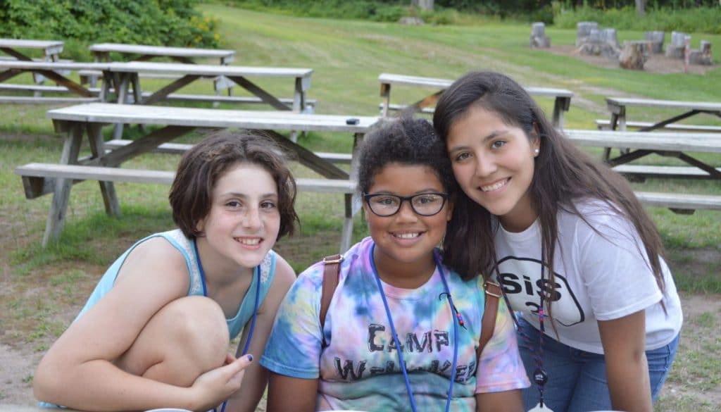 Camper friends hanging out around the picnic tables at WeHaKee Camp for Girls.