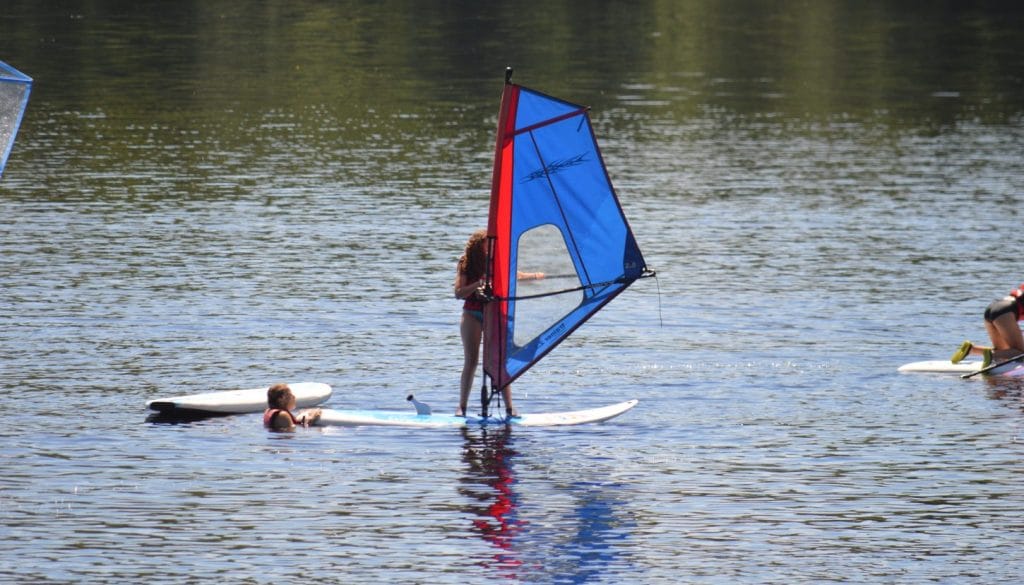 Campers paddle boarding with a sailor attached at WeHaKee Camp for Girls.