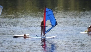 Campers paddle boarding with a sailor attached at WeHaKee Camp for Girls.