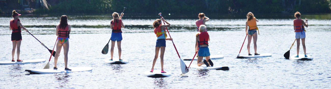 Campers at WeHaKee Camp for Girls standing on Paddle board on Hunter Lake.