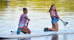 WeHaKee Camp for Girls campers kneeling on "Beach Bum" paddle boards on Hunter Lake.