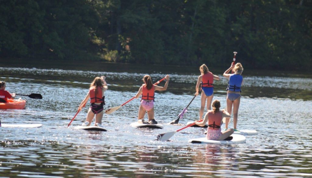 WeHaKee Camp for Girls Campers paddle boarding on Hunter Lake during water activities.