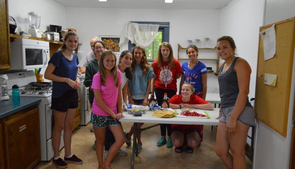 WeHaKee girls posing around a table as they make a strawberry dessert