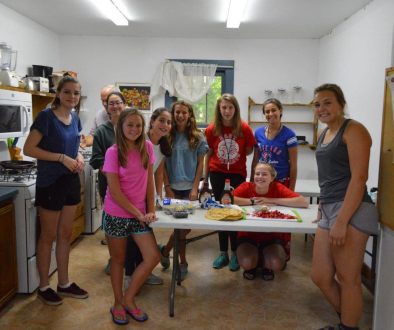 WeHaKee girls posing around a table as they make a strawberry dessert