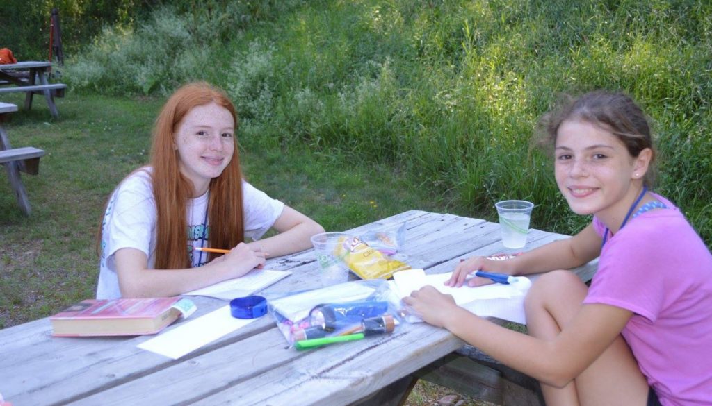 Two WeHaKee campers enjoying time together on a picnic table