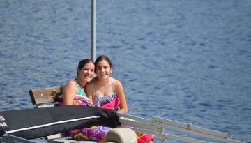 WeHaKee Camp for Girls camper friends sitting on a bench on the dock.