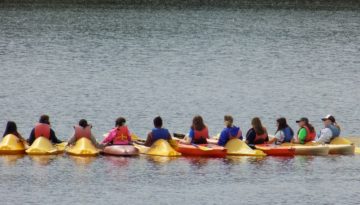 WeHakee Camp for Girls campers linking arms in kayaks.