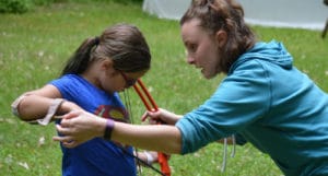 WeHaKee Camp For Girls employee assisting a camper with archery.